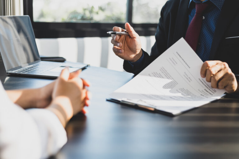 Businessman in suit in his office showing an insurance policy and pointing with a pen where the policyholder must to sign. Insurance agent presentation and consulting insurance detail to customer. advanced estate planning