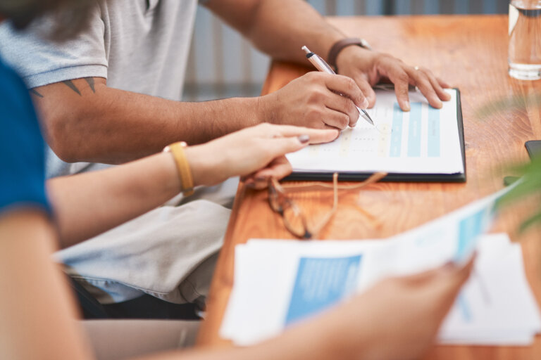 Couple, hands and sign of document, table and legal in office, life cover or insurance with pen. Paperwork, people and agreement of contract, glasses and together for marriage, love and retirement business succession planning